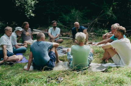 Männer in einem Kreis sitzen im Gras