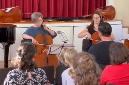 Zwei Frauen spielen konzentriert Cello vor Publikum